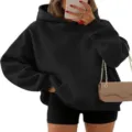 Detalle de sudadera con capucha oversize negra, hombros caídos, estilo urbano y cómodo. - S / Negro