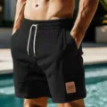 Men's black textured athletic shorts detail, featuring white drawstring and stylish leather patch. - S / Black