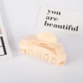 Close-up detail of a minimalist cream scalloped hair claw clip for elegant hair styling. - Off White