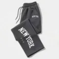 Detailed close-up of dark grey loose drawstring sweatpants with white letter prints. - Dark Gray