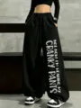 Detail view of black wide-leg sweatpants featuring bold vertical English print on leg. - S / Black