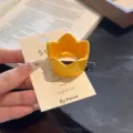 Detailed close-up of a cute yellow crown hair clip with backing card, cute cosplay accessory. - L