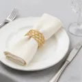 Anneau de serviette tissé doré en gros plan sur assiette blanche, table élégante. - Style Tissé Or (xm-6300)