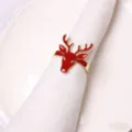 Close-up of red enamel and gold Christmas reindeer napkin ring detail for holiday table setting. - Reindeer Napkin Ring