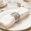 Silberner geflochtener Serviettenring Detail auf weißem Teller für elegante Tischdeko. - Silber