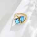 Detailed shot of the asymmetric twin blue cubic zirconia ring with gold-plated geometric band. - Size 6 / Sapphire Blue Stone Style Gold