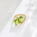 Close-up of the 18K gold plated two-stone green cubic zirconia open bypass ring detail. - Size 6 / Olive Green Style Gold