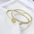 Elegantes vergoldetes offenes Armreif-Set mit funkelnden Kristallblüten und Solitär-Motiven. - Stil mit fünfblättrigen Blüten / Gold