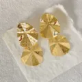 Nahaufnahme von goldenen, gedrehten geometrischen Ohrringen mit strukturierter Optik. - Doppelschicht-Gedreht-Geometrischer Stil (2)