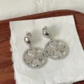 Detalle en primer plano de pendientes de trébol de circonita plateada para ropa de banquete. - Estilo Trébol de Cuatro Hojas Plateado (1) / Plateado