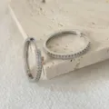 Primo piano dettagliato di eleganti orecchini a cerchio in zircone su superficie in pietra. - Stile Cerchio Argento