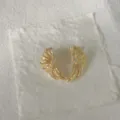 Primo piano dettagliato di orecchini a conchiglia dorati con zirconi microincastonati. - Forma a Ventaglio di Conchiglia (G2) / Oro