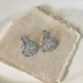 Primo piano di eleganti orecchini argentati a forma di foglia con zirconi scintillanti. - Forma a Foglia Increspata / Argento