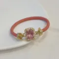 Dettaglio di bracciale in pelle intrecciata rosa con chiusura dorata in zircone quadrato. - Rosa