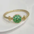 Primo piano dettagliato del bracciale dorato intrecciato con chiusura in zircone verde. - G Verde