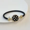 Schwarzes geflochtenes Lederarmband mit vergoldetem floralem Zirkon-Mittelstück Detail. - Schwarz