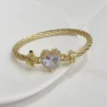 Vista di dettaglio di un bracciale intrecciato placcato oro con cristallo a cuore. - G Bianco