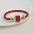 Primo piano del bracciale in pelle rossa con pietra rettangolare dorata e zirconi brillanti. - Rosso