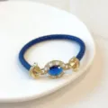 Vista dettagliata del lussuoso bracciale in pelle blu con zircone cubico ovale placcato oro. - Blu
