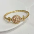 Detail shot of 18k gold plated twisted cable bangle with sparkling zircon center stone. - Champagne