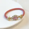 Vista dettagliata del lussuoso bracciale in pelle rosa intrecciata con zircone ovale. - Rosa
