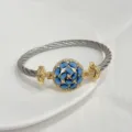Two-tone twisted cable bracelet with 18k gold plated round blue cubic zirconia center piece. - Blue