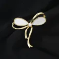 Elegante broche de lazo dorado con nácar y perla, accesorio chic para suéter o abrigo de invierno. - Lazo / Dorado y Blanco