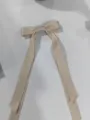 Primer plano de un elegante pasador de pelo con lazo doble de cinta color champán. - Marfil
