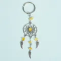 Handmade yellow crystal dreamcatcher keychain with silver wing charms on blue background - Citrine
