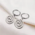 Primo piano dettaglio di orecchini a cerchio con ciondolo a spirale in acciaio inox. - Orecchini / Argento