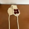 Detailansicht des beigen Strick-Ohrenwärmers mit handgehäkelten roten Blumen und Bändern. - Einheitsgröße / Beige