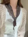 Close-up detail of a sweet floral triangular scarf with beaded charms worn on the neck. - Color #14
