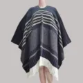 Detailed view of the ethnic style knitted poncho with fringe hem and warm striped pattern. - Pullover Shawl in Navy Blue
