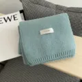Detalle de bufanda de invierno de punto suave en azul claro con etiqueta de marca. - Azul Fresco