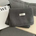 Primer plano detallado de una bufanda de invierno de punto gris oscuro doblada con etiqueta. - Gris oscuro