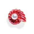 Gedetailleerde close-up van de rode emaille schelp broche met een centraal parelelement. - Geëmailleerde zeeschelpbroche - rood