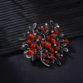 Detailed close-up of retro tree branch brooch, featuring red stones and antique silver leaves. - Antique Pewter
