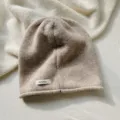 Primer plano detallado del acogedor gorro de lana tejido en color beige con textura y etiqueta. - Sombrero / Caqui