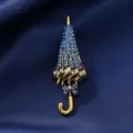 Close-up detail of the creative blue rhinestone umbrella brooch, vintage gold alloy lapel pin. - Long Handle Umbrella Blue