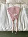 Detailansicht des rosa Strick-Ohrwärmers mit süßem Aufnäher und Bändern, weiche Textur. - Einheitsgröße / Hellrosa