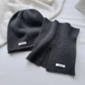 Detalle del conjunto de gorro y bufanda de lana gris oscuro, textura suave y etiqueta. - Conjuntos / Gris
