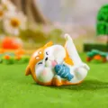 Close-up of cute resin shiba inu figurine holding a small blue fish for car decor. - 19799 Slacking Shiba