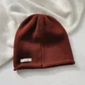 Primer plano de un acogedor gorro de pura lana marrón rojiza con textura de punto fina. - Sombrero / Rojo