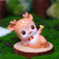 Close-up detail of a cute cartoon deer figurine with big eyes and bow, placed on a wood slice. - Yellow Sideways Lying (A036-A)