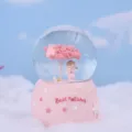 Pink snow globe detail shot, featuring cherry tree and cute angel figurine inside base. - 5H133 Large Snowing with Lights & Music / Standing Angel Girl
