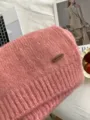 Weiches Strickschal Detailbild zeigt kuschelige Textur, rosa Winterschal mit Holzschild. - Rosa