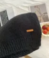 Alpakawolle Mischung weicher Strick Schal Detailansicht mit Leder Etikett und warmer Textur. - Schwarz