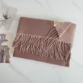 Detailaufnahme eines weichen mauvefarbenen Fransen-Winter-Kaschmirschals auf Marmor. - Dunkelbraun