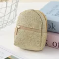 Close-up detail shot of sparkling gold mini backpack coin purse pendant with metal zipper closure. - Brown