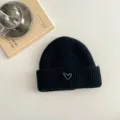 Detailansicht der schwarzen Kinder Strickmütze mit süßem weißem gestickten Herzmotiv. - Schwarzer Hut
